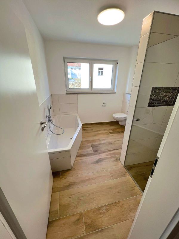 Badezimmer mit Badewanne, Dusche, WC und Holzboden nach Renovierung in Ingolstadt von Renovierung & Sanierung ALBAN