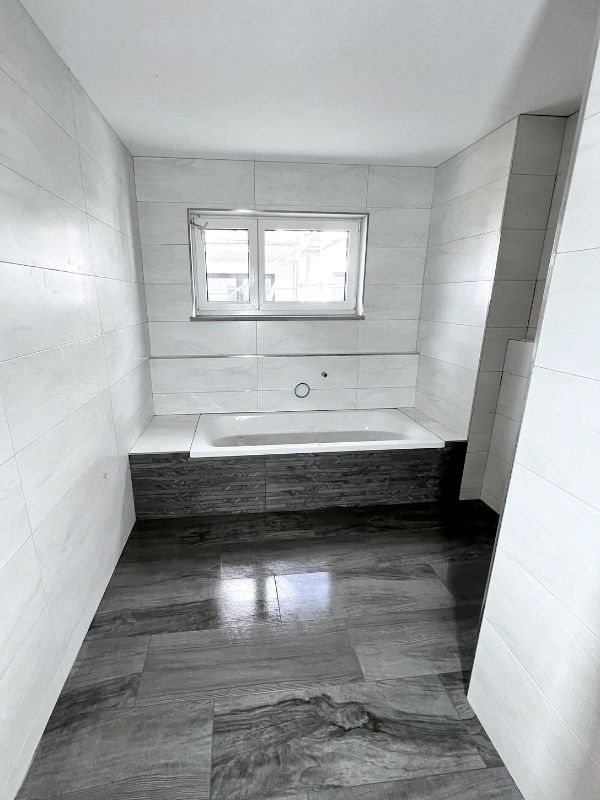 Badezimmer mit Badewanne und grauen Fliesen nach Renovierung in Ingolstadt von Renovierung & Sanierung ALBAN