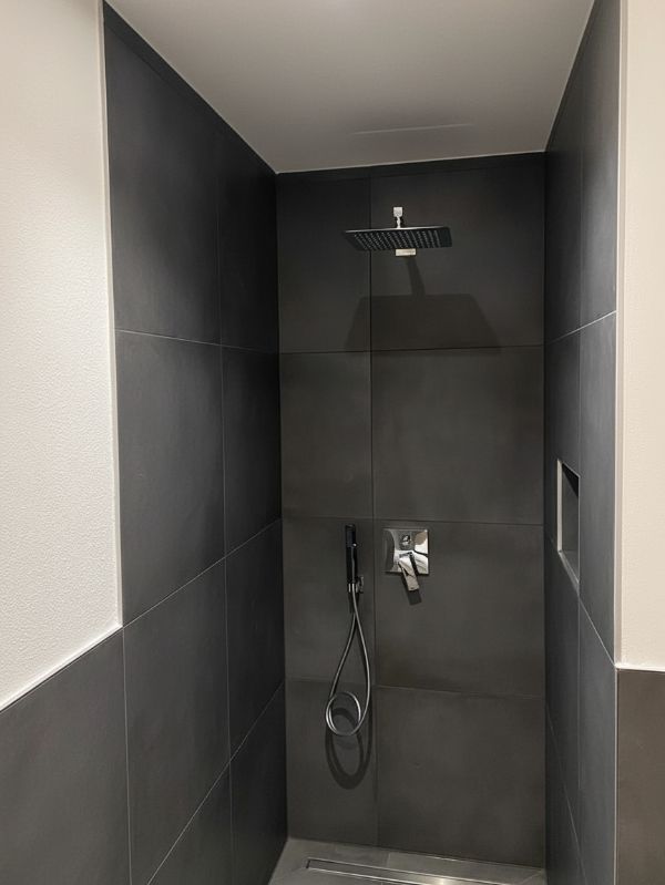 Moderne bodengleiche Dusche mit schwarzen Fliesen im Badezimmer in Ingolstadt von Renovierung & Sanierung ALBAN
